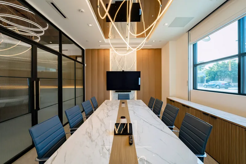 Conference room with long marble-look table and blue chairs, Los Angeles