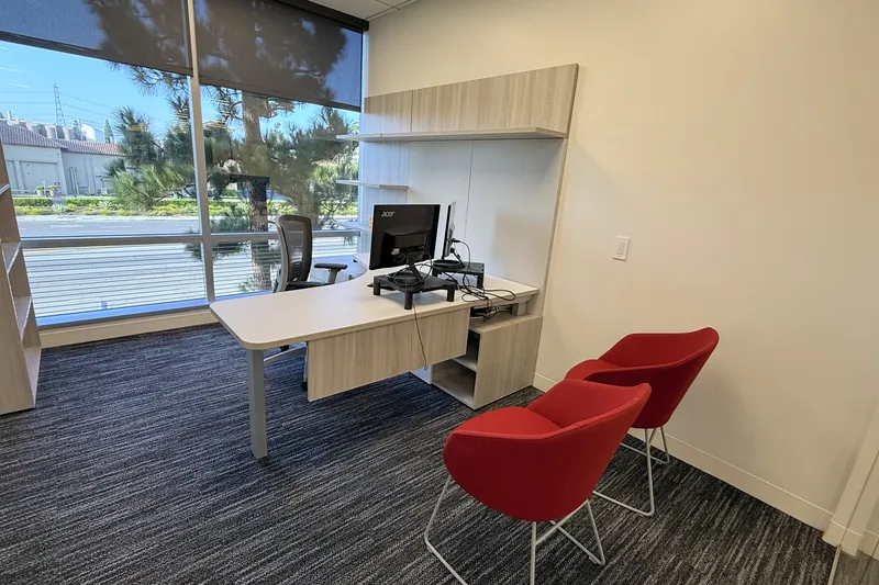 Private office with height-adjustable desk and red side chairs, El Segundo