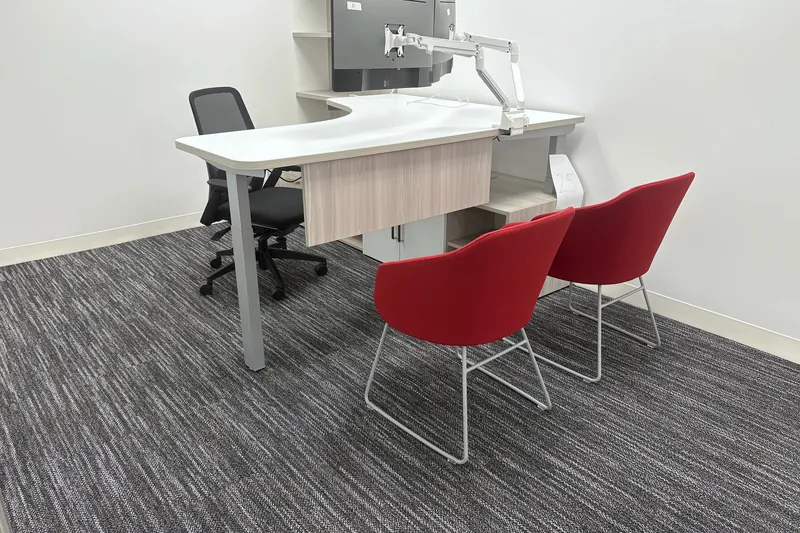 Private office with curved sit-stand desk and red side chairs, El Segundo
